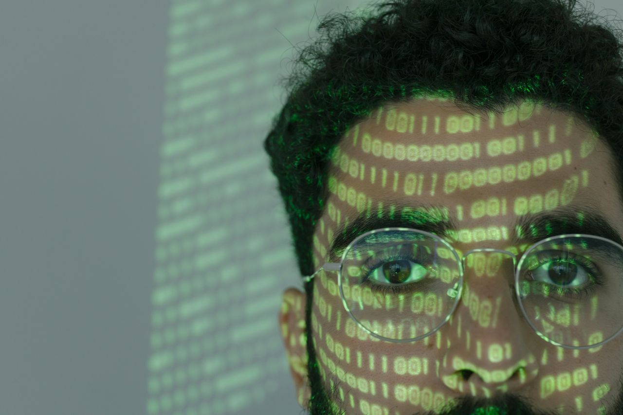 Services Close-up of a man with binary code projected on his face, symbolizing cybersecurity.